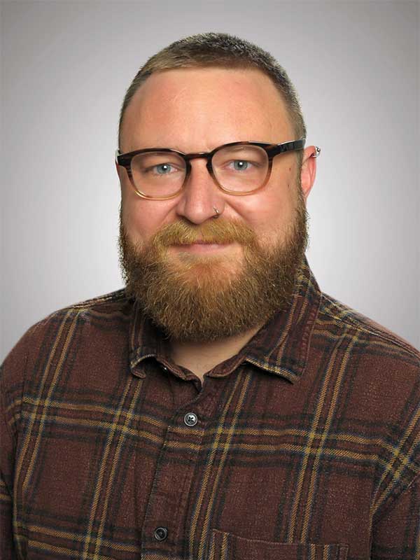 Danny Zuber Mann mit Brille und Bart vor grauem Hintergrund